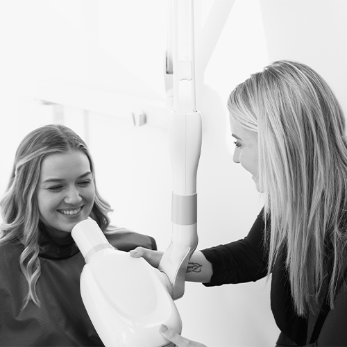 Black and White photo of a Dental A Team hygienist performing X-rays on a patient.