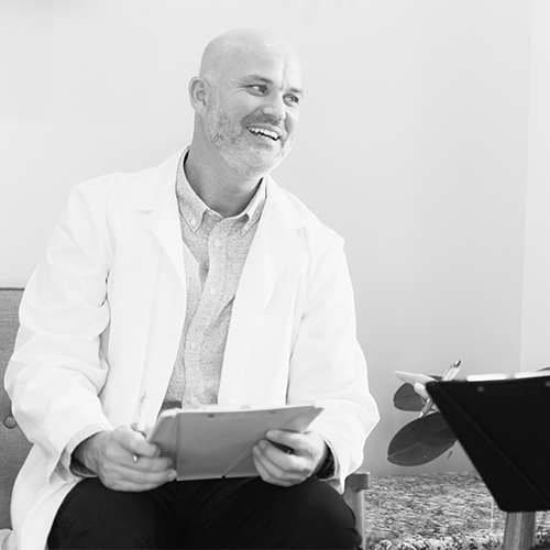 Black and white photo of the doctor and Kiera Dent talking while looking over clipboards.