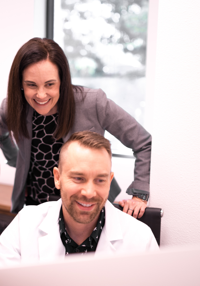 Team member looking over doctor's shoulder, both looking at the screen