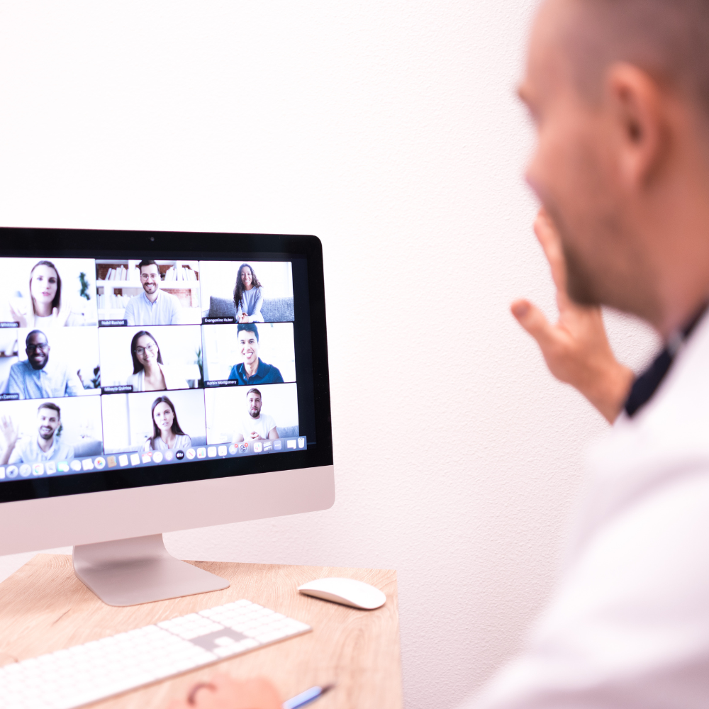 Dentist attending a virtual meeting, looking at the screen and waving
